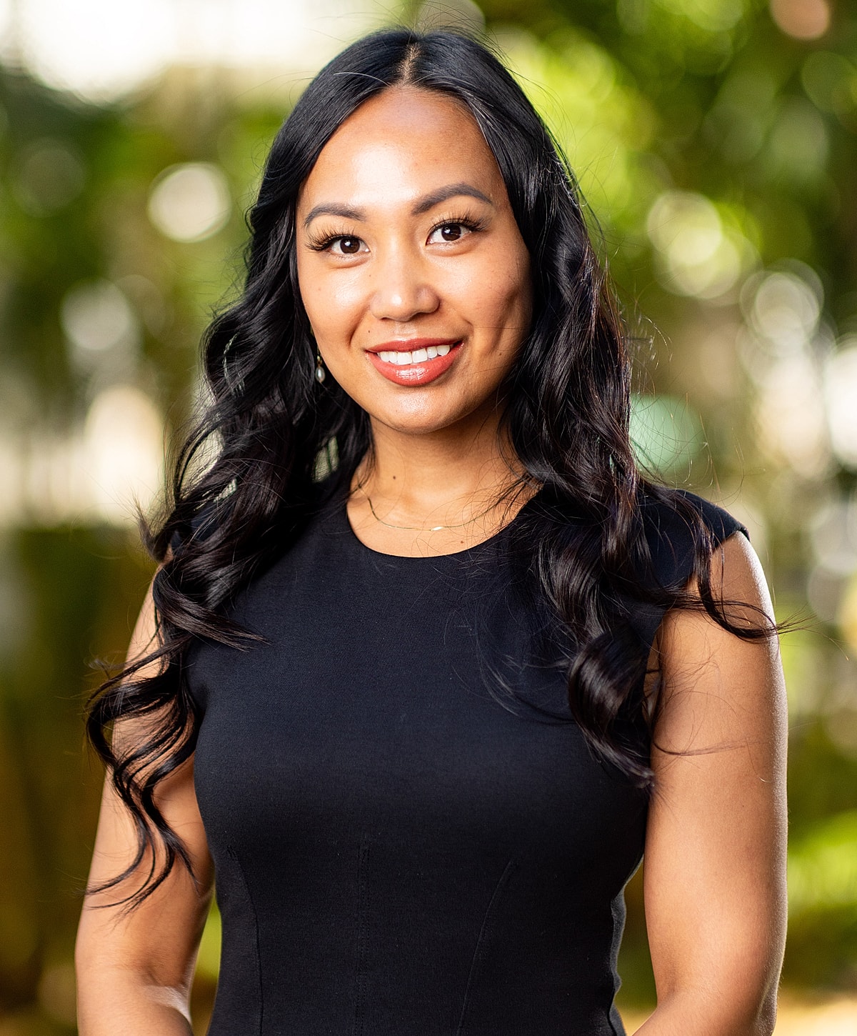 Smiling woman with wavy hair in outdoor setting.