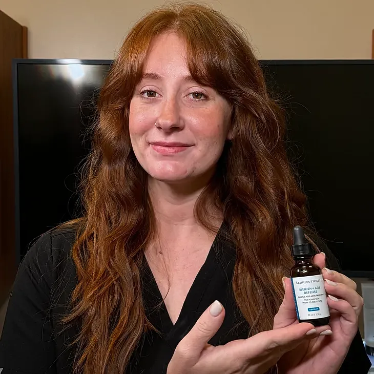 Person holding skincare serum in front of camera.