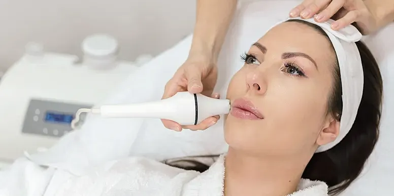Facial treatment using beauty device on woman.