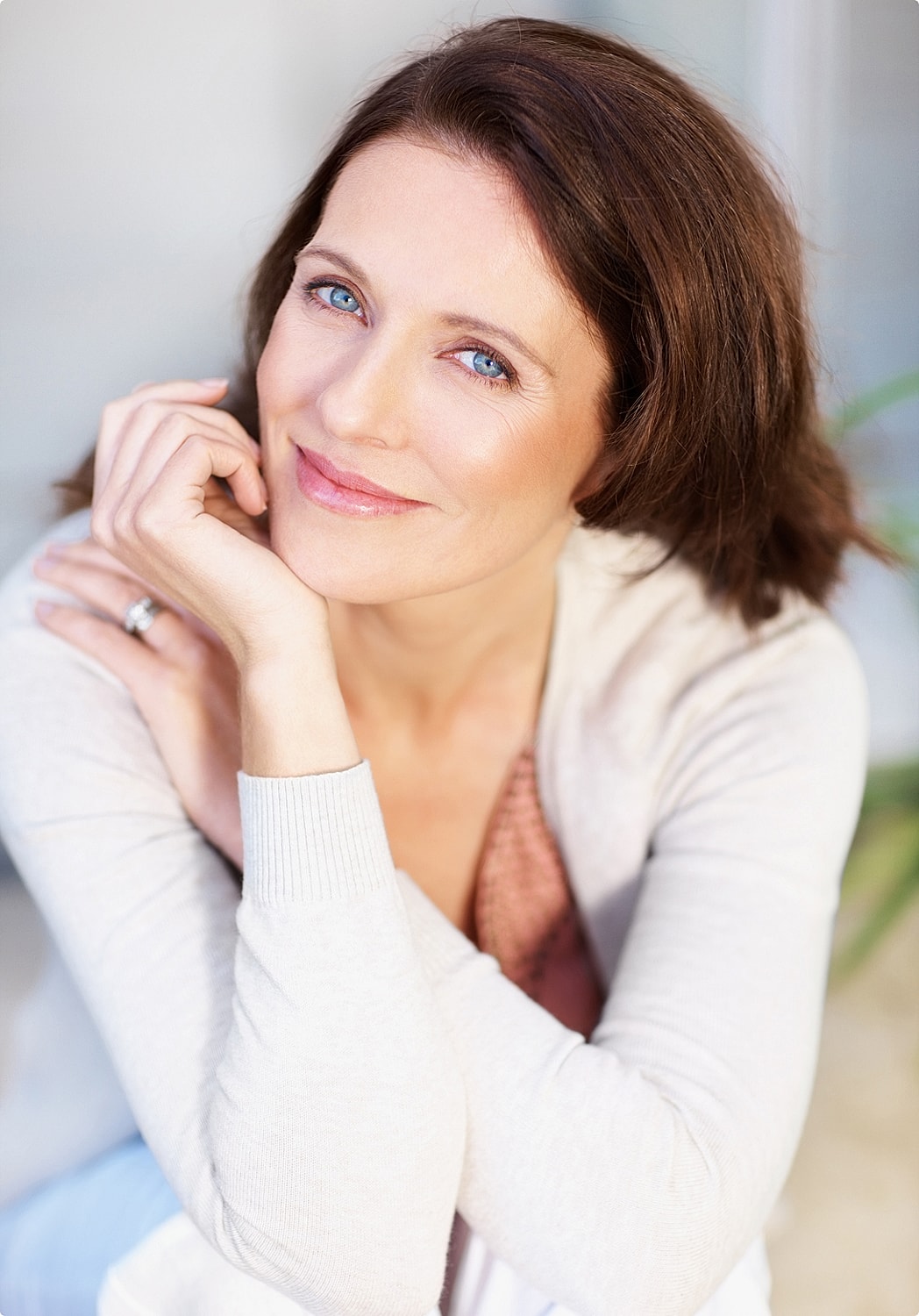 Smiling woman with blue eyes resting her chin.
