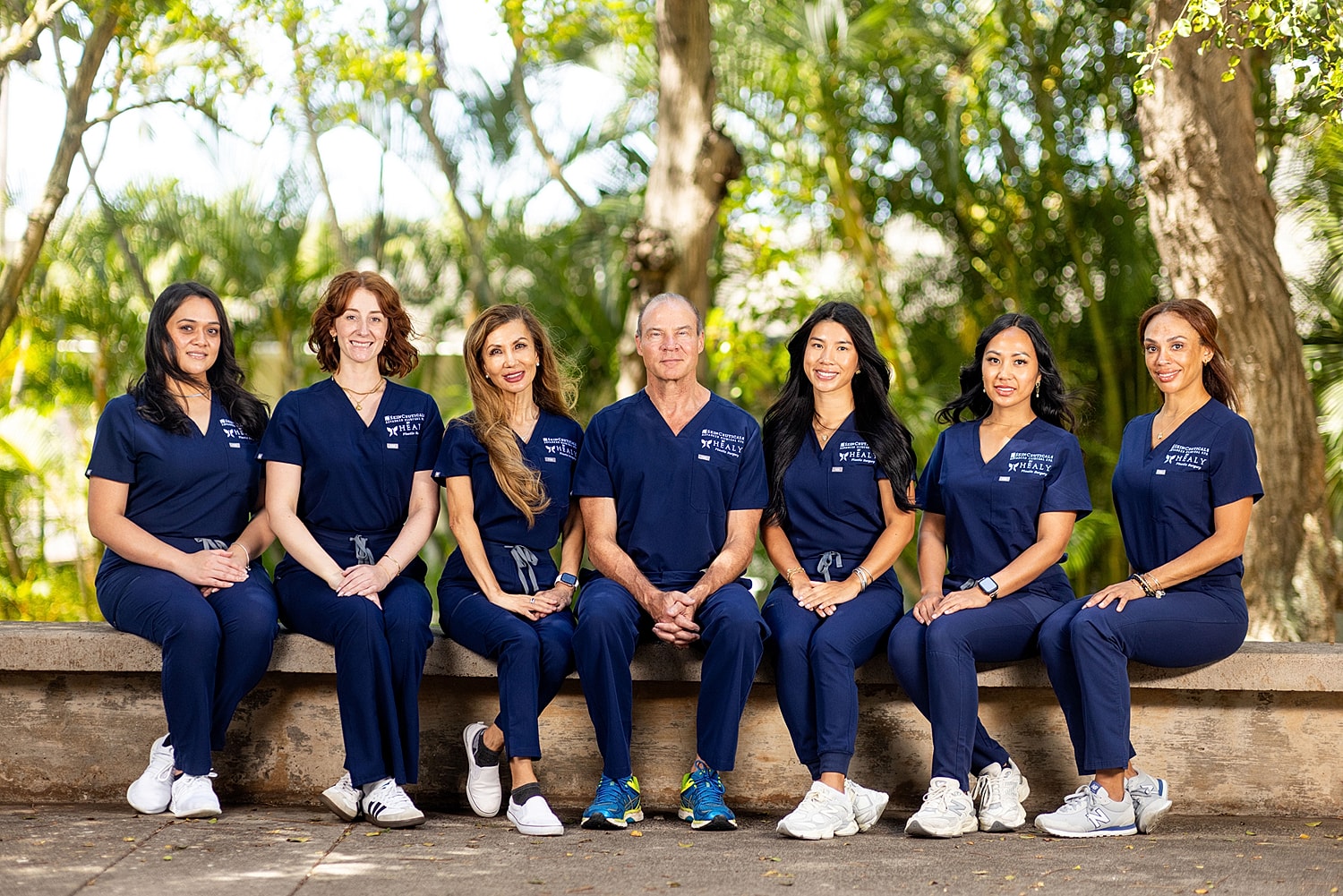 Medical professionals posing outdoors in scrubs.